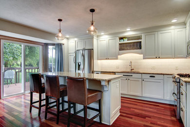 Inspiration for a timeless l-shaped medium tone wood floor and red floor eat-in kitchen remodel in Chicago with a drop-in sink, recessed-panel cabinets, granite countertops, beige backsplash, ceramic backsplash, stainless steel appliances, an island and white cabinets
