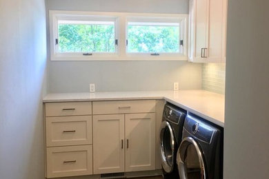 Example of a minimalist l-shaped porcelain tile and black floor dedicated laundry room design in Minneapolis with an undermount sink, shaker cabinets, white cabinets, quartz countertops, blue walls, a side-by-side washer/dryer and white countertops