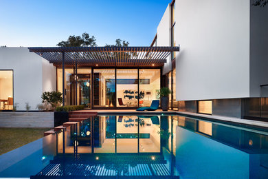 Example of a trendy backyard rectangular infinity pool design in Austin