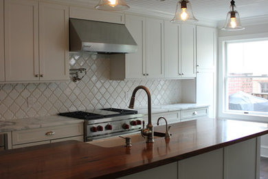 Example of a large transitional galley dark wood floor eat-in kitchen design in Baltimore with a farmhouse sink, shaker cabinets, white cabinets, wood countertops, white backsplash, ceramic backsplash, stainless steel appliances and an island