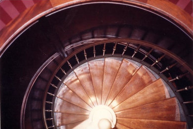 Ejemplo de escalera de caracol clásica con escalones de madera y barandilla de metal