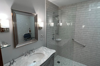 Bathroom - mid-sized transitional 3/4 gray tile and ceramic tile ceramic tile and single-sink bathroom idea in Chicago with recessed-panel cabinets, gray cabinets, a two-piece toilet, gray walls, an undermount sink, marble countertops and a freestanding vanity