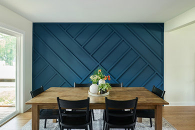 Idées déco pour une salle à manger ouverte sur la cuisine moderne en bois de taille moyenne avec un mur bleu, un sol en bois brun, aucune cheminée et un sol marron.