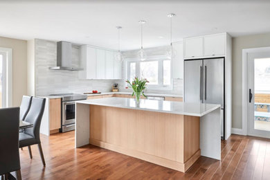 Design ideas for a mid-sized scandinavian l-shaped open plan kitchen in Ottawa with flat-panel cabinets, light wood cabinets, grey splashback, with island, white benchtop, an undermount sink, quartz benchtops, stainless steel appliances, medium hardwood floors, brown floor and porcelain splashback.