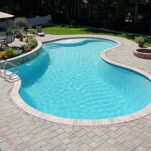 Klassisk inredning av en mellanstor njurformad baddamm på baksidan av huset, med en fontän och marksten i betong