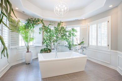 Freestanding bathtub - large transitional master gray tile and porcelain tile porcelain tile and brown floor freestanding bathtub idea in Chicago with raised-panel cabinets, white cabinets, gray walls, an undermount sink, solid surface countertops and black countertops