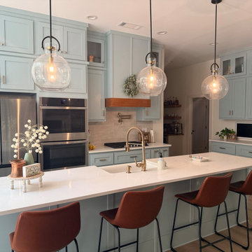 Spacious Blue-Green Kitchen with Large Island and Glass Pendants
