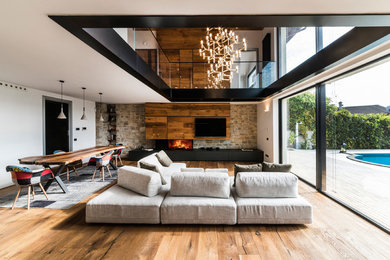 Idee per un ampio soggiorno design stile loft con pareti bianche, pavimento in legno massello medio, camino ad angolo, cornice del camino in legno, parete attrezzata e sala formale