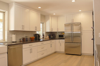 Large minimalist u-shaped bamboo floor and beige floor open concept kitchen photo in Phoenix with a farmhouse sink, shaker cabinets, white cabinets, quartzite countertops, white backsplash, mosaic tile backsplash, stainless steel appliances and a peninsula