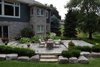 This is an example of a large transitional backyard patio in Toronto with an outdoor kitchen and a roof extension.