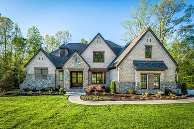 Example of a large classic beige two-story brick exterior home design in Other with a shingle roof