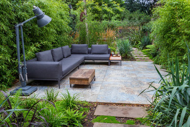Large contemporary backyard patio in London with concrete pavers and no cover.