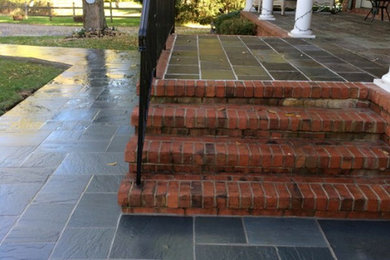 Mid-sized elegant front yard stone patio photo in New York with a roof extension