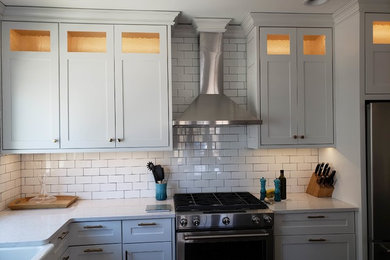Minimalist dark wood floor and brown floor kitchen photo in Milwaukee with white cabinets, quartzite countertops, white backsplash, subway tile backsplash and white countertops