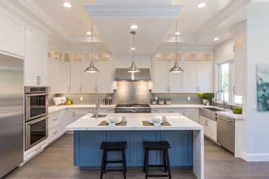 Example of a trendy u-shaped gray floor and medium tone wood floor eat-in kitchen design in San Francisco with a farmhouse sink, shaker cabinets, white cabinets, quartz countertops, gray backsplash, glass tile backsplash, stainless steel appliances, an island and white countertops