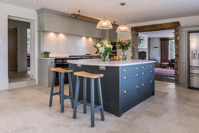 Mid-sized trendy ceramic tile and beige floor eat-in kitchen photo in Cardiff with gray cabinets, white backsplash, ceramic backsplash and an island