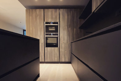 Idee per una cucina abitabile moderna con lavello sottopiano, ante lisce, ante nere, top in granito, paraspruzzi nero, paraspruzzi in granito, elettrodomestici neri, pavimento in legno massello medio e top nero