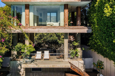 Inspiration for a mid-sized contemporary beige two-story wood and board and batten exterior home remodel in Los Angeles with a metal roof and a gray roof