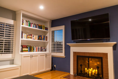 Large elegant open concept medium tone wood floor and brown floor family room photo in Los Angeles with blue walls, a standard fireplace, a wood fireplace surround and a wall-mounted tv