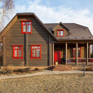 Exempel på ett lantligt brunt hus, med två våningar och halvvalmat sadeltak