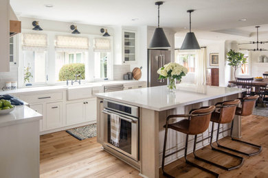 Example of a large cottage u-shaped eat-in kitchen design in San Francisco with a farmhouse sink, beaded inset cabinets, white cabinets, beige backsplash, subway tile backsplash, stainless steel appliances and an island