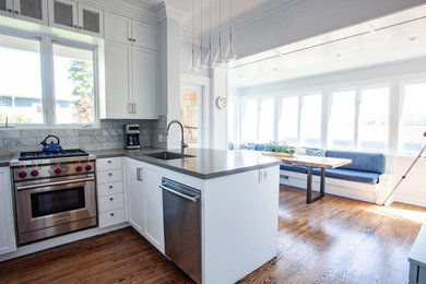 Mid-sized transitional u-shaped medium tone wood floor and brown floor eat-in kitchen photo in Sacramento with an undermount sink, white cabinets, quartz countertops, gray backsplash, stainless steel appliances and an island