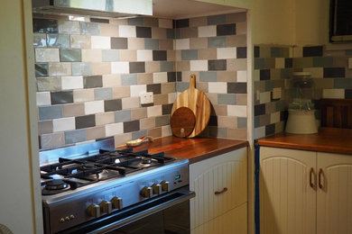 This is an example of a country kitchen in Other with wood benchtops and multi-coloured splashback.