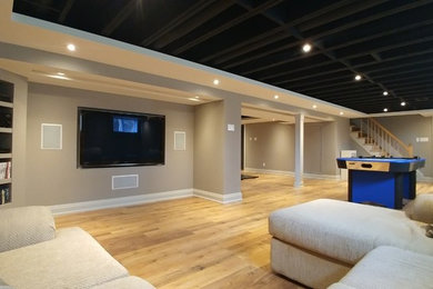 Huge trendy underground laminate floor basement photo in Ottawa with gray walls
