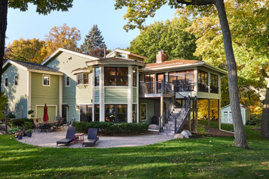Cette photo montre une grande façade de maison verte tendance en panneau de béton fibré et bardage à clin à un étage avec un toit à deux pans, un toit en shingle et un toit marron.