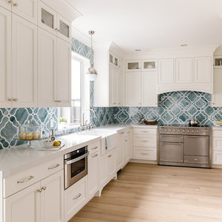 Idee per una cucina ad U classica di medie dimensioni con lavello stile country, ante con riquadro incassato, ante bianche, top in quarzo composito, elettrodomestici da incasso, parquet chiaro, paraspruzzi blu e paraspruzzi con piastrelle di vetro