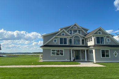 Photo of an expansive beach style three-storey grey house exterior in Portland Maine with wood siding, a shed roof and a shingle roof.