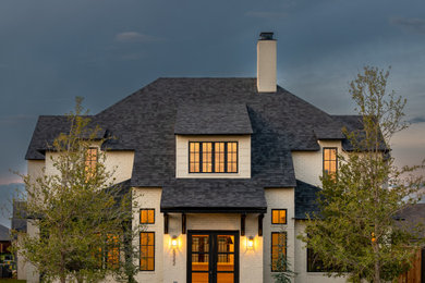 Example of a large trendy beige two-story brick house exterior design in Austin with a shingle roof and a gray roof