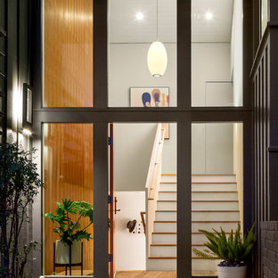 Foto di un grande ingresso moderno con pareti bianche, una porta singola, una porta arancione e parquet chiaro