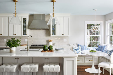 Mid-sized transitional medium tone wood floor and brown floor eat-in kitchen photo in DC Metro with white cabinets, beige backsplash, subway tile backsplash, stainless steel appliances, an island, white countertops, an undermount sink and shaker cabinets