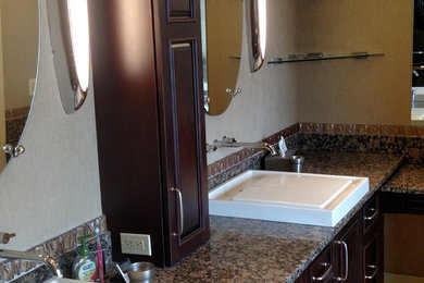 Example of a large master bathroom design in Omaha with dark wood cabinets and granite countertops