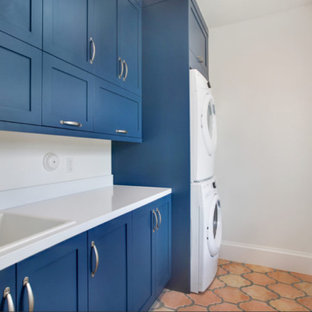 This is an example of a medium sized classic galley separated utility room in Miami with a built-in sink, shaker cabinets, blue cabinets, composite countertops, white walls, terracotta flooring and a stacked washer and dryer.