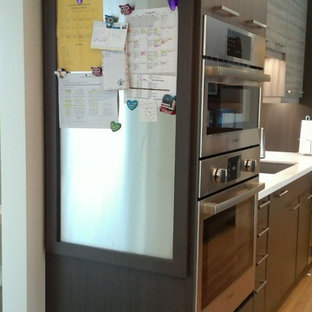 Mid-sized modern kitchen pantry designs - Mid-sized minimalist galley light wood floor and yellow floor kitchen pantry photo in Calgary with an undermount sink, flat-panel cabinets, dark wood cabinets, quartzite countertops, gray backsplash, glass tile backsplash, stainless steel appliances and an island