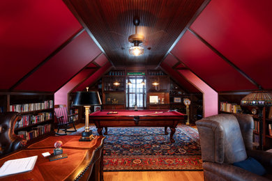 Family room library - loft-style medium tone wood floor, wood ceiling and wall paneling family room library idea in Boston with red walls