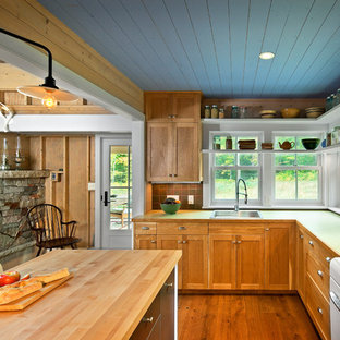 Diseño de cocina en L, de estilo de casa de campo, de tamaño medio, abierta, con fregadero encastrado, armarios estilo shaker, puertas de armario de madera oscura, encimera de madera, salpicadero marrón, electrodomésticos blancos, suelo de madera en tonos medios y una isla