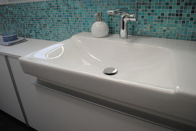 Diseño de cuarto de baño actual con armarios con paneles lisos, puertas de armario blancas, baldosas y/o azulejos azules y baldosas y/o azulejos en mosaico