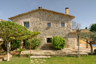 Ejemplo de fachada de casa beige y blanca rural grande de dos plantas con revestimiento de piedra, tejado a dos aguas, tejado de teja de barro y escaleras