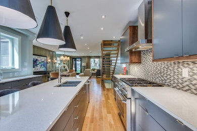 Eat-in kitchen - large transitional galley light wood floor and multicolored floor eat-in kitchen idea in Toronto with a double-bowl sink, flat-panel cabinets, gray cabinets, quartz countertops, beige backsplash, ceramic backsplash, stainless steel appliances and an island
