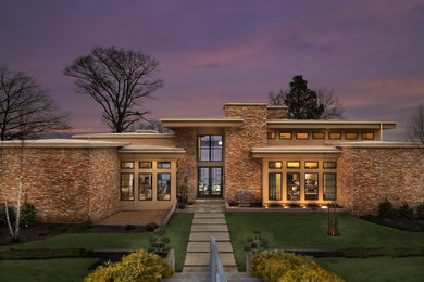 Large contemporary beige three-story stone flat roof idea in Other