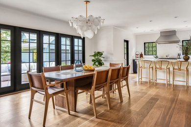 This is an example of a mid-sized transitional separate dining room in Los Angeles with white walls, medium hardwood floors, a two-sided fireplace, a tile fireplace surround, beige floor and decorative wall panelling.