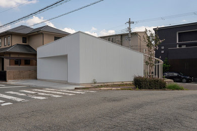This is an example of a small industrial one-storey white house exterior in Osaka with metal siding, a shed roof and a metal roof.
