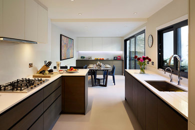 Large traditional galley eat-in kitchen in London with a double-bowl sink, flat-panel cabinets, granite benchtops, white splashback, stone slab splashback, panelled appliances, ceramic floors and a peninsula.