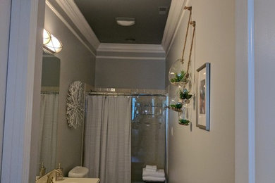 Sliding shower door - mid-sized transitional porcelain tile and beige floor sliding shower door idea in St Louis with recessed-panel cabinets, gray cabinets, a two-piece toilet, gray walls, an integrated sink and quartz countertops