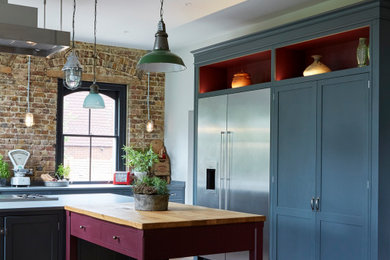 Design ideas for an expansive eclectic kitchen in London with pink cabinets, wood benchtops, shaker cabinets, stainless steel appliances and multiple islands.