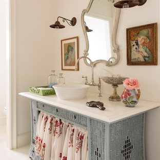 Cette photo montre une salle d'eau bord de mer de taille moyenne avec une vasque, un placard en trompe-l'oeil, des portes de placard bleues, un plan de toilette en quartz modifié, un mur blanc et un sol en bois peint.