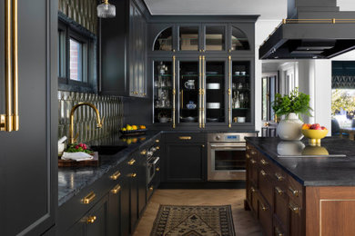 Example of a mid-sized trendy l-shaped open concept kitchen design in Denver with black cabinets, soapstone countertops, green backsplash, ceramic backsplash, paneled appliances, an island and black countertops